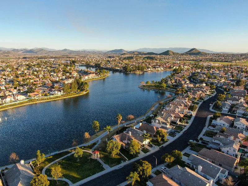 A suburban neighborhood surrounding a large lake with mountains in the background.