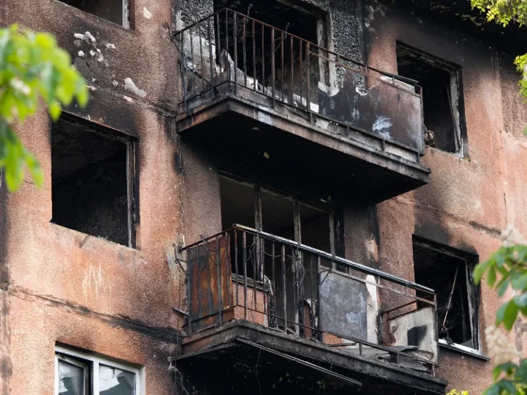 Burned apartment building with charred balconies and broken windows.
